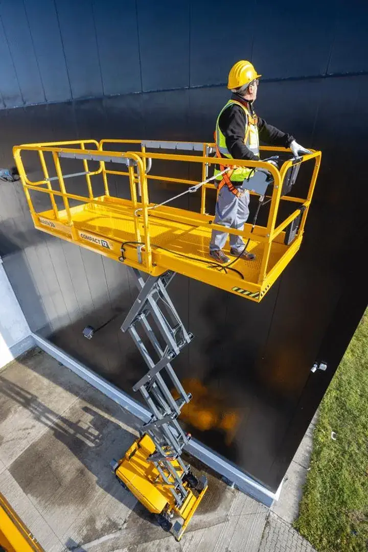 Operario trabajando desde una plataforma tijera sobre una fachada