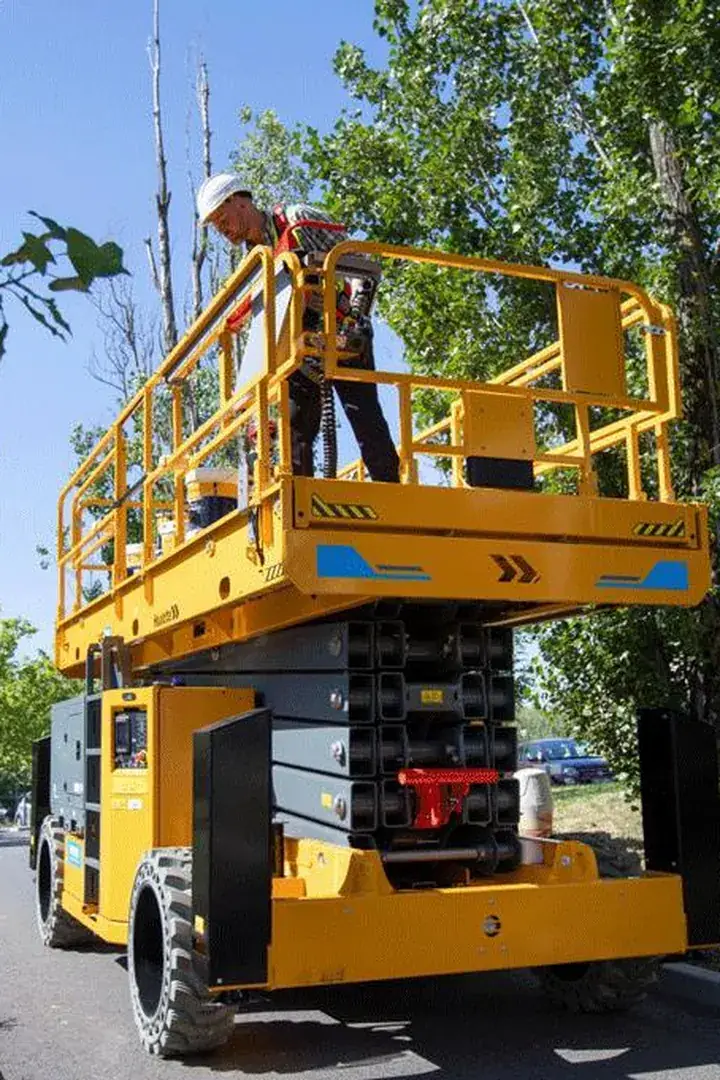 Plataforma tijera trabajando en exterior entre arbolado